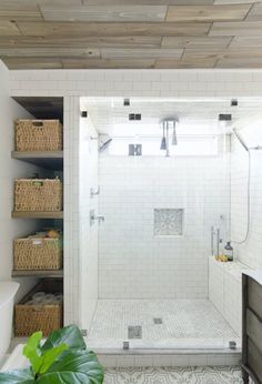 a bathroom with white tile and wood ceilinging, including a walk - in shower