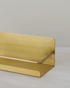 a gold metal object on a white surface