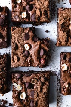 brownies with chocolate chips and nuts are arranged on a white surface