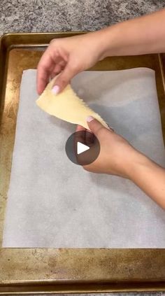 a person is kneading dough on top of a sheet of paper in a baking pan