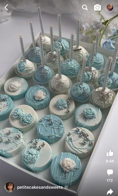 a box filled with lots of blue and white cupcakes