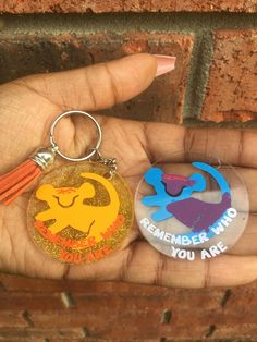 someone is holding two different key chains in their hand, one has an animal and the other has a lion on it