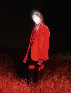 a person standing in the grass wearing a red jacket