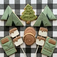 some cookies are arranged in the shape of tents and trees on a black and white checkered tablecloth