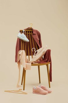 a wooden chair with clothes on it and a pair of pink shoes next to it