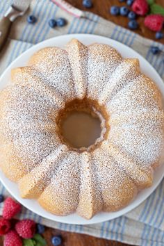 a bundt cake with powdered sugar on top and berries around the edges, ready to be eaten