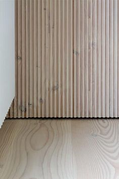 the corner of a room with wood slats on it's walls and floor