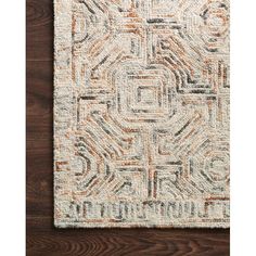 a rug with an orange and white design on the bottom, in front of a wooden floor