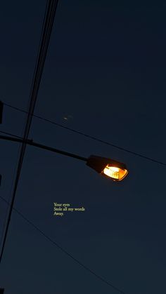 a street light with the moon in the background and some power lines above it at night