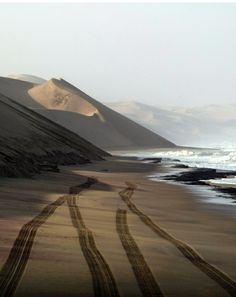 there is a dirt road going through the sand dunes