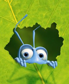 a blue bug with eyes sitting on top of a green leaf