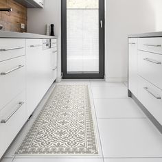 a kitchen with white cabinets and floor tiles