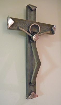 a metal cross mounted to the wall with two rings hanging from it's sides