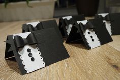 three black and white cards with bows on them sitting on top of a wooden table