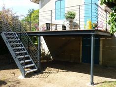 an outdoor patio with stairs leading up to the roof and potted plants on top