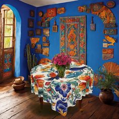 a dining room with blue walls and wooden flooring, decorated with colorful floral designs