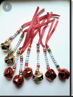 a group of red and gold bell ornaments on a white surface with ribbon around them