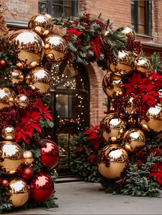 two christmas trees with gold and red ornaments on them in front of a brick building