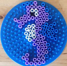 a blue plate with purple and white circles on it sitting on a wooden table top