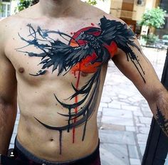 a man with a bird tattoo on his chest is standing in front of a building