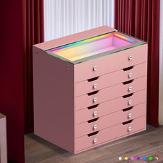 a pink dresser with many drawers in front of a red curtain