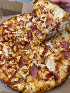 a person is taking a slice of pizza from a cardboard box that has been partially eaten