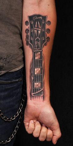 a person with a guitar tattoo on their arm and hand, holding an electric guitar