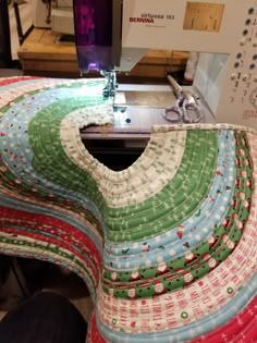 a close up of a sewing machine on a table with many pieces of fabric in front of it