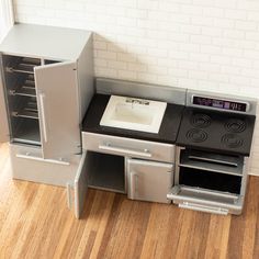 a toy stove and oven in the shape of a refrigerator with its door open on a wooden floor