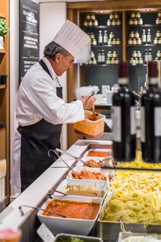 a chef preparing food in a kitchen with pasta and sauces on the counter top