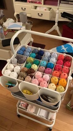 a cart filled with lots of yarn and crochet hooks on top of a hard wood floor