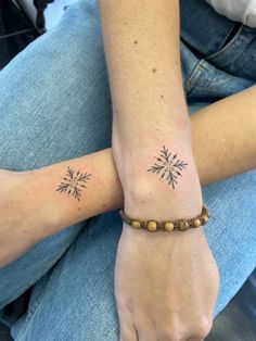 two people with matching tattoos on their arm and wrist are sitting next to each other