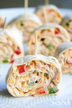 chicken salad wrapped in tortilla with toothpicks on the top and garnished with tomatoes