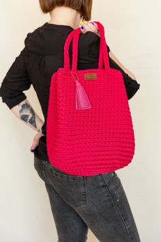 a woman holding a pink crocheted bag