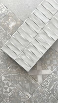 a tile floor with white and grey tiles on it, including an intricately designed design