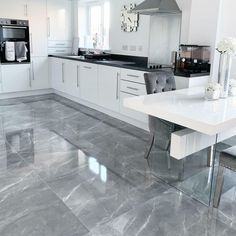 a modern kitchen with marble floors and white cabinets, stainless steel appliances and counter tops