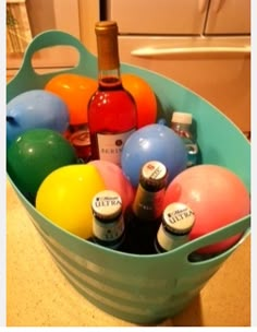 a bucket filled with lots of different types of balls and bottles in front of a refrigerator