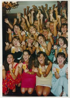 a group of women standing next to each other with their hands up in the air