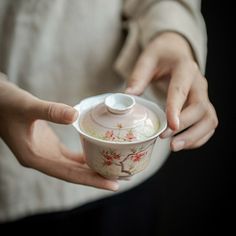 a woman is holding a tea cup in her left hand and the lid has flowers on it