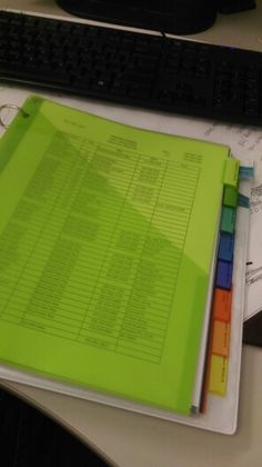 a green binder sitting on top of a desk next to a keyboard