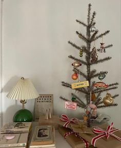 a small christmas tree sitting on top of a table next to boxes and a lamp