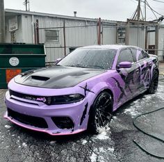 a purple and black car is parked in the parking lot with snow on its tires