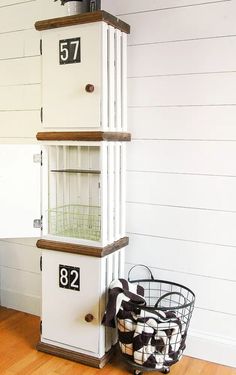 a white cabinet sitting on top of a wooden floor next to a basket filled with flowers