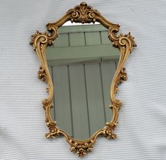 an ornate gold mirror hanging on the side of a wall