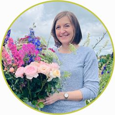 a woman holding a bouquet of flowers in front of a blue sky and green circle