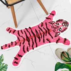 a pink tiger rug on the floor next to a chair and potted houseplant