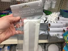 a person holding up a package of toilet paper in front of some other items on the shelf