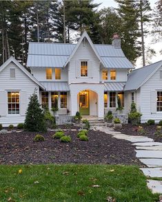 a large white house with lots of windows and lights on it's front porch