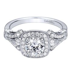 a white gold engagement ring with an intricate halo setting and round diamonds on the band