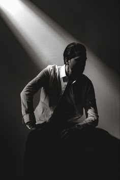 a man sitting on top of a chair under a spotlight